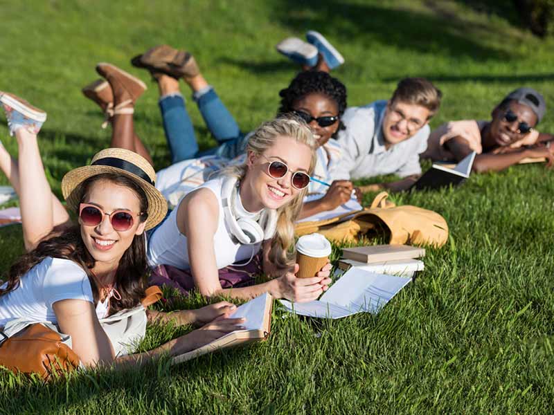 A group of young people enjoy books in the park.